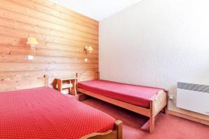 um quarto com uma cama vermelha e paredes de madeira em Quartier Crève Cœur - maeva Home - Duplex 3 Pièces 8 Personnes Confort 03 em Valmorel