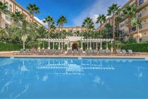 a large swimming pool with chairs and a building at Orsini Luxury Retreat: 2BR/2BA in Los Angeles