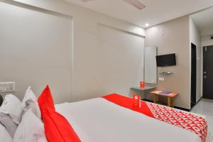 Schlafzimmer mit einem roten und weißen Bett und einem TV in der Unterkunft OYO Nova Hotel Nildeep in Rajkot