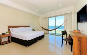 Schlafzimmer mit einem Bett, einem Schreibtisch und einem TV in der Unterkunft Hotel Summer Frente Al Mar in Cartagena de Indias