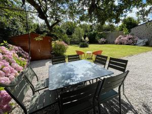 a table and chairs in a yard with flowers at Maison de charme vue sur mer pour 6 pers in Quinéville