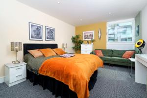 ein Schlafzimmer mit einem Bett und einem grünen Sofa in der Unterkunft COBALT POINT, South Quay in London