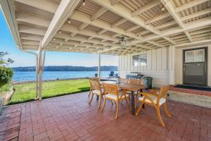 een patio met een tafel en stoelen en uitzicht op het water bij 116 - Inviting Waterfront Haven BBQ in Gig Harbor