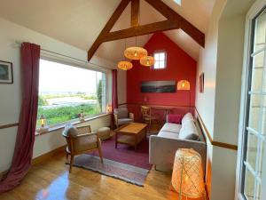 un soggiorno con pareti rosse e una grande finestra di Maison de charme vue sur mer pour 6 pers a Quinéville
