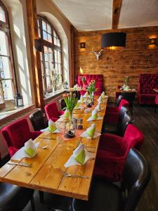 einen langen Holztisch in einem Restaurant mit roten Stühlen in der Unterkunft Hotel-Restaurant Thüringer Hof in Bad Frankenhausen