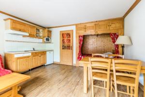 a kitchen with wooden cabinets and a table and chairs at Résidence Les Balcons d'Anaïte - maeva Home - Studio Cabine 5/6 Personnes C 63 in Les Houches