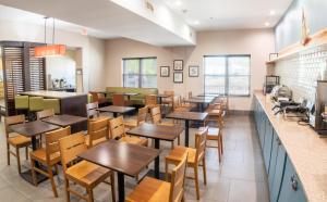 un restaurante con mesas y sillas de madera y una barra en Country Inn & Suites by Radisson, Wilmington, NC, en Wilmington