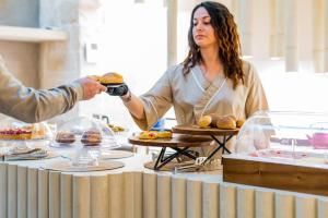 Uma mulher está a dar um hambúrguer a uma pessoa. em Vico Bianco Raro Villas Smart Rooms Collection em Ostuni