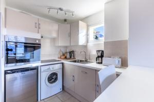 a kitchen with white cabinets and a washer and dryer at Appartement 6 pers. à 30m des remontées - maeva Home - Appartement vue montagne 3 pièces 6 personnes - Sélection MAE-8716 in L'Alpe-d'Huez +7 photos