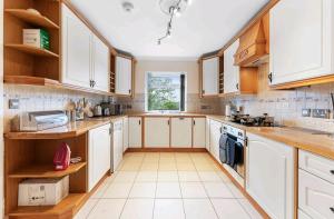 a large kitchen with white cabinets and a window at Spacious & bright home with parking, ensuite, view in Tremadoc