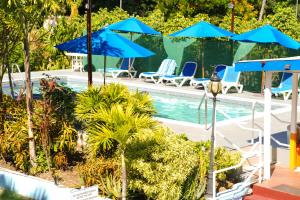a swimming pool with blue umbrellas and chairs at Vedanta Resort Barbados in Bridgetown