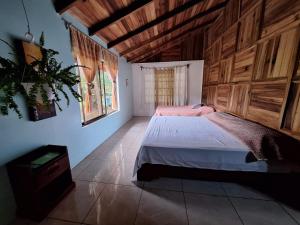 a bedroom with a bed with a wooden wall at VILLA ESMERALDA in Siquirres