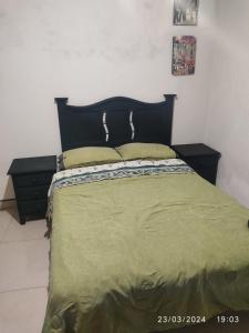 1 cama con edredón verde y 2 almohadas amarillas en Cómoda y agradable habitación con baño privado en Uruapan del Progreso