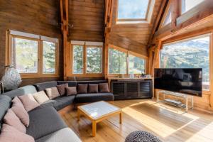 een woonkamer met een bank en een tv bij Chalet Arketa 14 pers. au pied des pistes - Maeva Particuliers - 8 Pièces 14 Personnes Prestige 139510 in Avoriaz