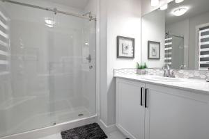 a white bathroom with a shower and a sink at Beautiful 3Bed-with AC-Close to Spruce Meadows & Mountains in Calgary