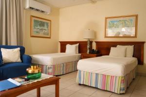 a hotel room with two beds and a blue chair at Vedanta Resort Barbados in Bridgetown +30 photos