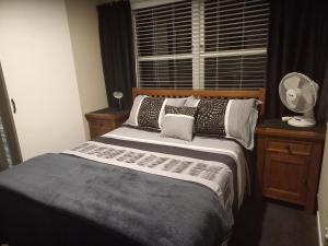a bedroom with a bed and a window with a fan at Lakeview's On Richmond in Taupo
