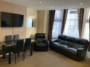 a living room with a black leather couch and a table and chairs at Phillips Apartments in Blackpool