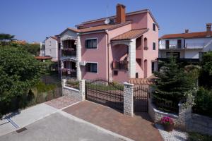 ein rosa Haus mit einem Zaun und einer Auffahrt in der Unterkunft Apartments Daniela in Novigrad Istria