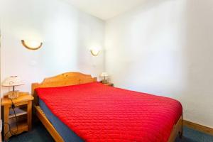 a bedroom with a bed with a red bedspread at Quartier La Forêt - maeva Home - 3 Pièces 6 Personnes Sélection MAE-3341 in Valmorel