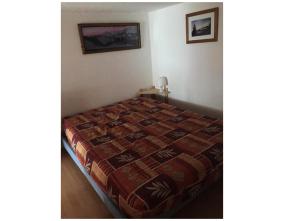 een slaapkamer met een bed met een quilt bij Résidences quartier Charmettoger - maeva Home - 2 Pièces 6 Personnes Budget 07 in Arc 1800