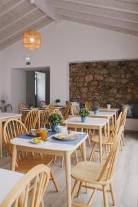 a dining room with tables and chairs and a stone wall at Pure Fonte Velha B&B in Vila do Bispo