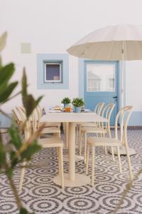 a dining room with a table and chairs with an umbrella at Pure Fonte Velha B&B in Vila do Bispo