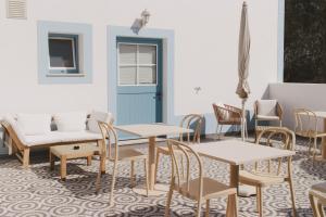 a room with tables and chairs and a blue door at Pure Fonte Velha B&B in Vila do Bispo
