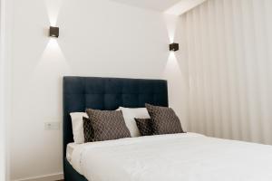 Bett mit blauem Kopfteil in einem Zimmer in der Unterkunft A 0.4 - Alexa Smart House in Braga