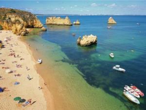 un groupe de personnes sur une plage avec des bateaux dans l'eau dans l'établissement Apartamento encantador a 100m da praia, à Carvoeiro