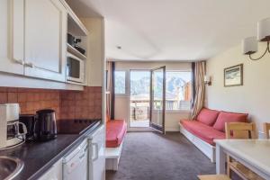 a kitchen and a living room with a red couch at Résidence Sépia - maeva Home - Appartement 2 pièces 5 personnes Sélection 66 in Morzine