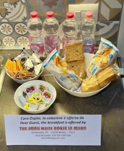 米兰The Small White House In Milan的一张桌子,上面放着三碗食物和瓶装水