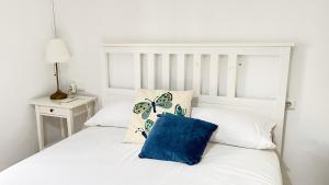 ein weißes Bett mit einem blauen Kissen darauf in der Unterkunft El Descanso del Indiano in Córdoba