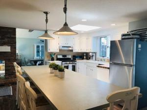 a kitchen with a large table and a refrigerator at Beautiful Cape Cod home! Steps to beach! in Mashpee