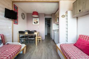 une pièce avec une table et des chaises et une cuisine dans l'établissement Résidence L'Ours Blanc - maeva Home - Appartement 2 Pièces 4 personnes - Sélection MAE-7573, à Huez