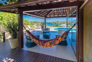a hammock on the deck of a house with a pool at Paraíso Buziano 1 in Búzios