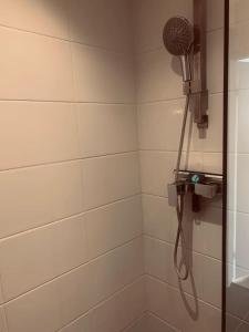 een douche met een douchekop in de badkamer bij Main Street beach apartment in Noordwijk