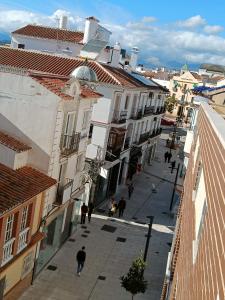 un grupo de personas caminando por una calle con edificios en Los Maestros: ático en el centro de Vélez-Málaga, en Vélez-Málaga