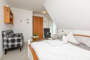 a bedroom with a white bed and a chair at Haus Delphin in Juist