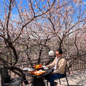 un hombre sentado en una mesa con un tazón de fruta en Olympia Garden Hotel, en Ereván