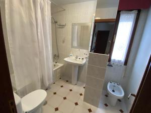 a white bathroom with a toilet and a sink at Vivienda de Uso turístico Paseo del Suaron Vegadeo in Vegadeo