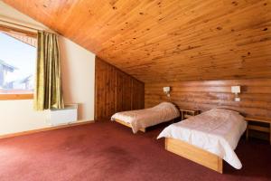 een slaapkamer met 2 bedden in een houten kamer bij Les Résidences de Valmorel - maeva Home - Appartement 3 pièces 8 personnes 81 in Valmorel