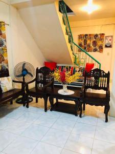 a living room with two chairs and a table with flowers at 15pax-U2-Rose&Fer Vigan Transient-Near Calle Crisologo in Bantay