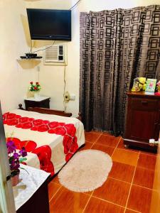 a bedroom with a bed with red sheets and a television at 15pax-U2-Rose&Fer Vigan Transient-Near Calle Crisologo in Bantay