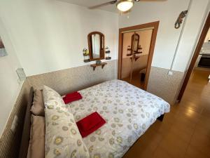 a bedroom with a bed with two red pillows on it at Lovely newly refurbished 1 Bedroom Flat Minutes From Sandy Beach,private terrace in Caleta De Fuste