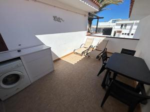 a balcony with a washing machine and a table and chairs at Lovely newly refurbished 1 Bedroom Flat Minutes From Sandy Beach,private terrace in Caleta De Fuste