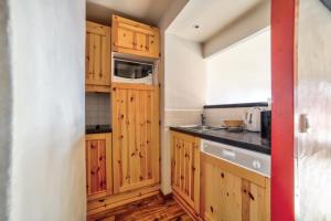 Una cocina con armarios de madera, fregadero y microondas. en Résidence Quartier Falaise - maeva Home - Appartement 3 pièces 6 personnes - Sélection MAE-2199, en Avoriaz