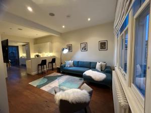 ein Wohnzimmer mit einem blauen Sofa und einer Küche in der Unterkunft Mrs K Stunning 3 bedrooms apartment Chelsea in London