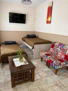 Habitación con 2 camas, sofá y mesa. en Chez Gla - Alojamiento Bariloche en San Carlos de Bariloche