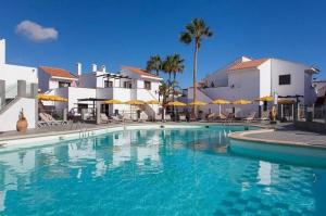 a swimming pool with blue water in front of buildings at Lovely newly refurbished 1 Bedroom Flat Minutes From Sandy Beach,private terrace in Caleta De Fuste